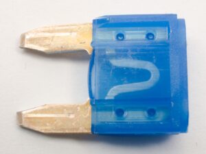 「ヒューズの写真：電流が規定値を超えると内部の導体が溶断して回路を遮断する、過電流保護用の電子部品。」